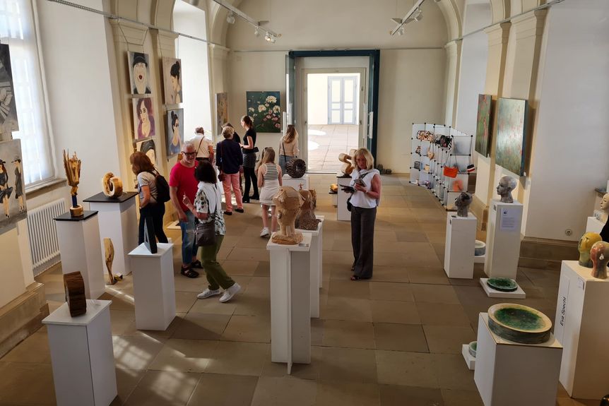 Historischer Ausstellungssaal, Kunstwerke an den Wänden und auf Sockeln, dazwischen Besucher